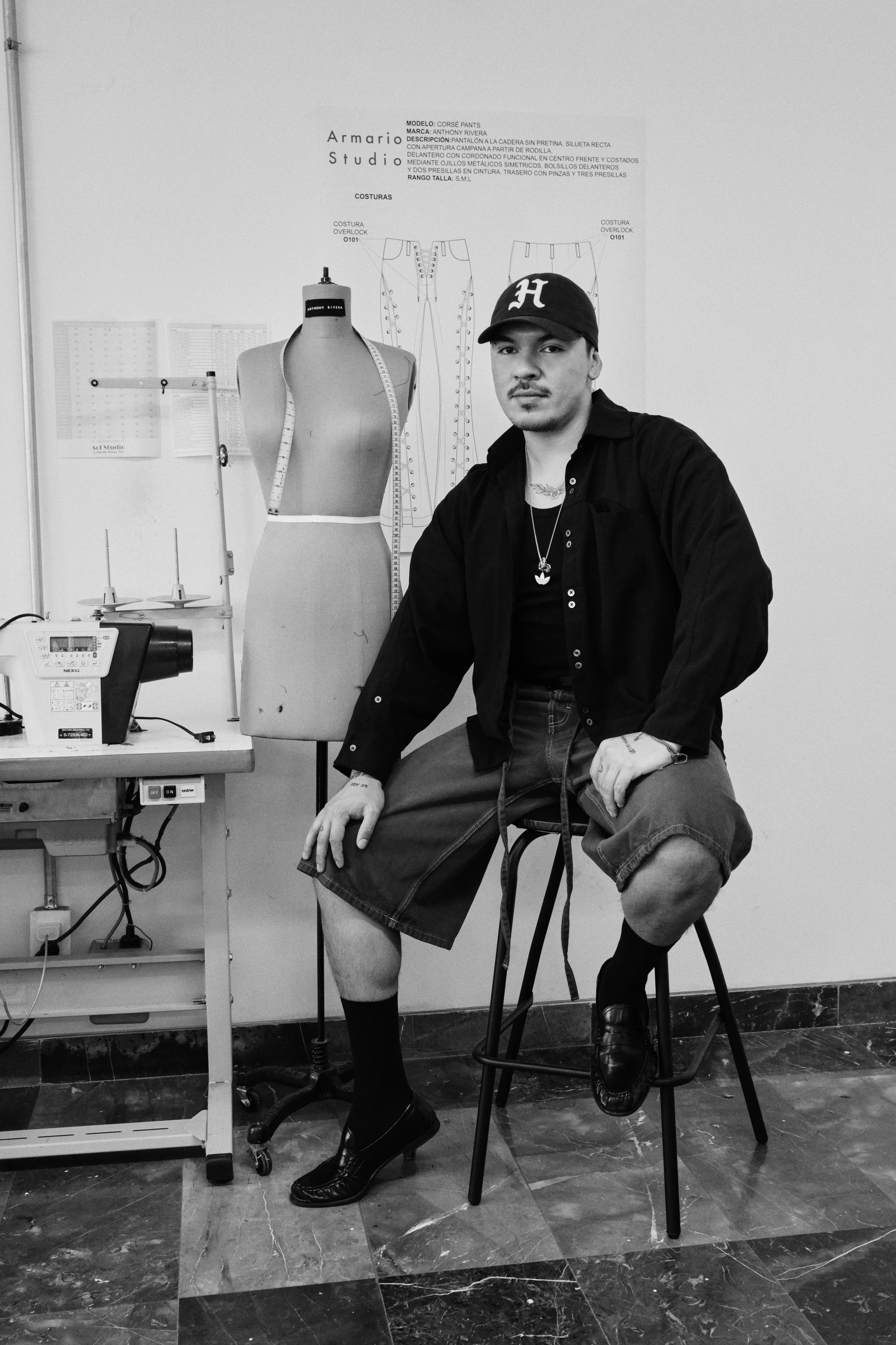 A figure in a studio, before a paper backdrop, beside the folio mark.